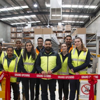 Specsavers employees in high vis, seen in a warehouse.